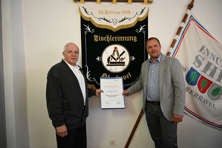 Kammerpräsident Robert Wüst (rechts) überreicht Norbert Fischer die Silbernen Ehrennadel der Handwerkskammer Potsdam
