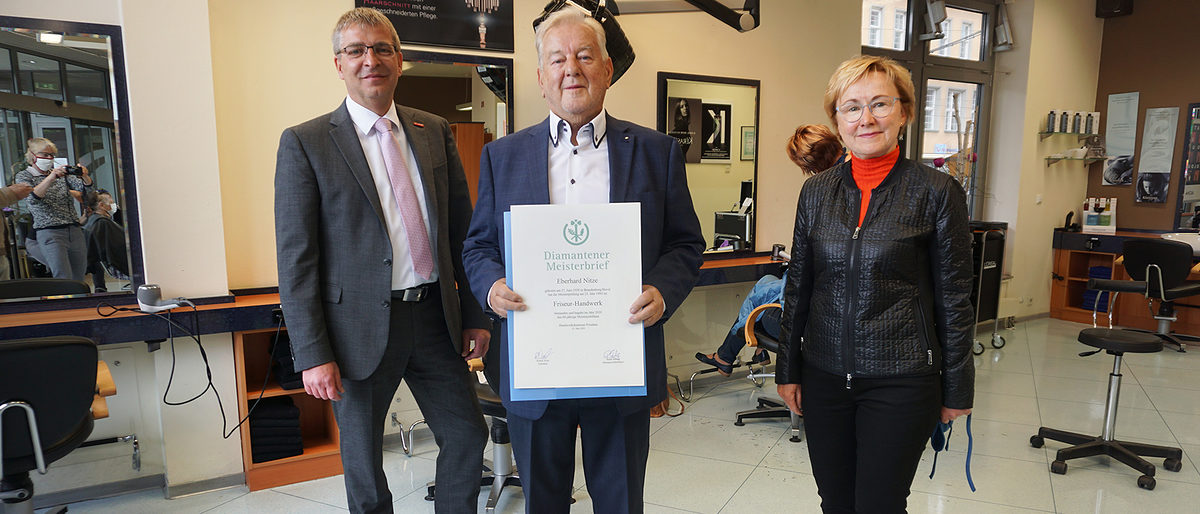 Ralph Bührig, Hauptgeschäftsführer der Handwerkskammer Potsdam, überreicht Eberhard Nitze den Diamantenen Meisterbrief im Beisein von Brita Meißner, heutige Geschäftsführerin der Neue Linie Friseur & Kosmetik GmbH Ralph Bührig, Hauptgeschäftsführer der Handwerkskammer Potsdam, überreicht Eberhard Nitze den Diamantenen Meisterbrief im Beisein von Brita Meißner, heutige Geschäftsführerin der Neue Linie Friseur & Kosmetik GmbH