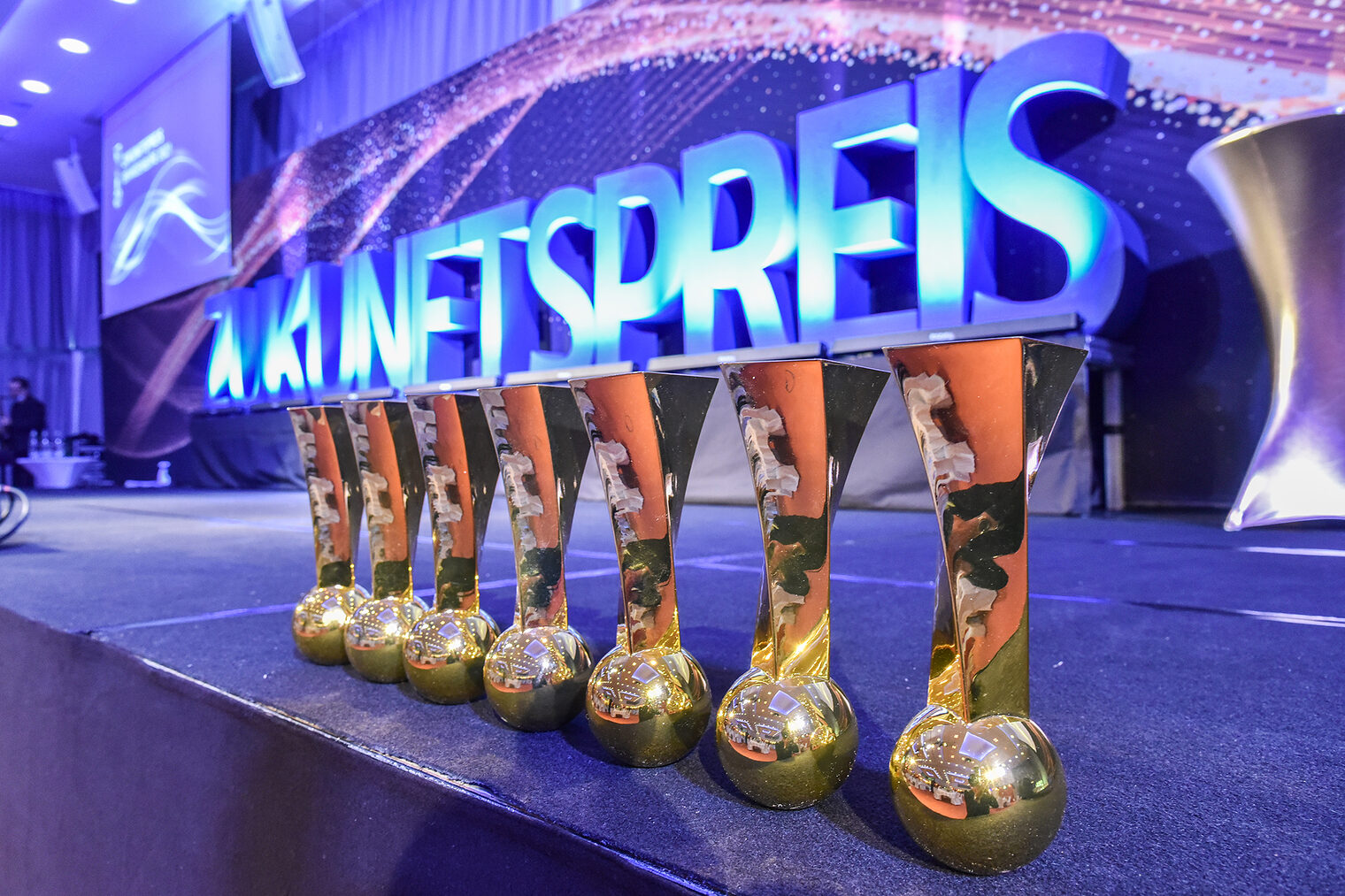 sieben Zukunftspreise in einer Reihe stehen auf einer violetten Bühne