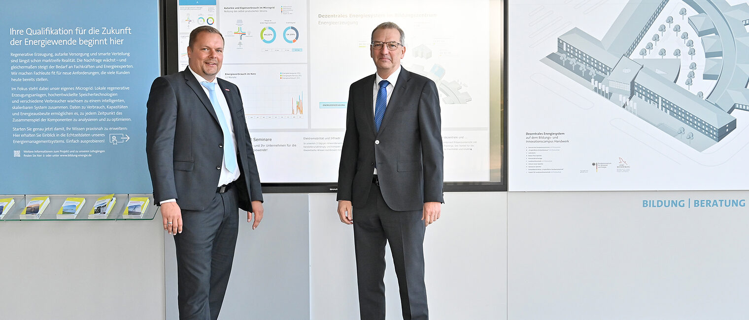 zwei Männer im Anzug vor einer Erklärtafel
