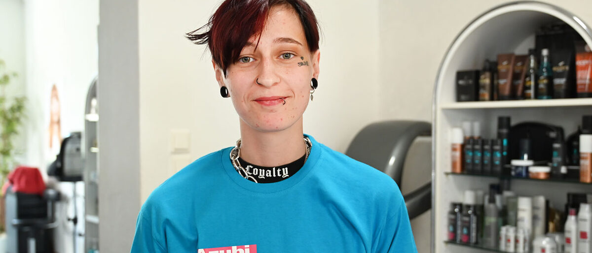 junge Frau im blauen T-Shirt mit der Aufschrift "Azubi des Monats Mai 2022. Das Handwerk"