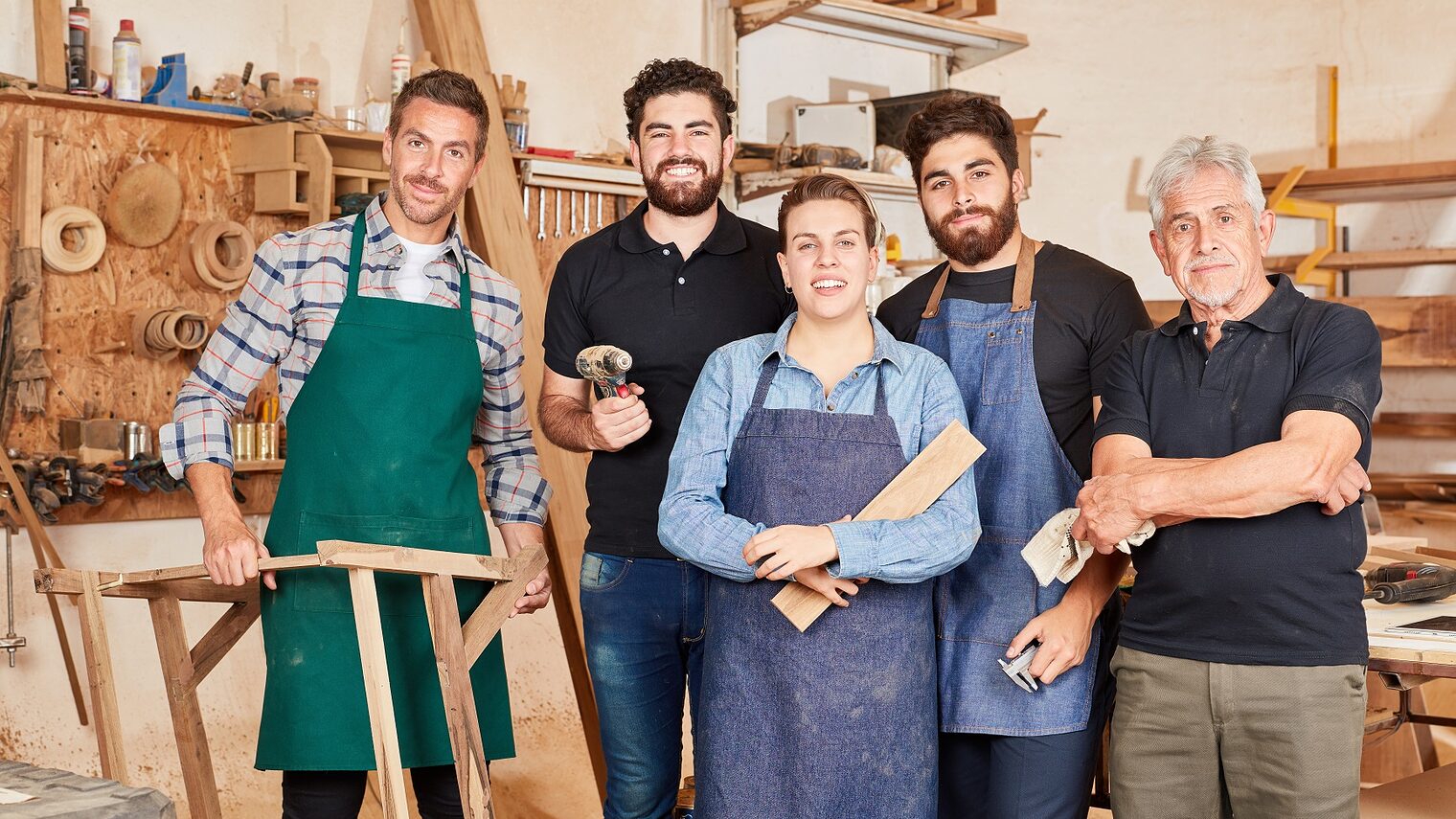 Handwerker Team mit Meister und Azubis in der Schreinerei oder Tischlerei