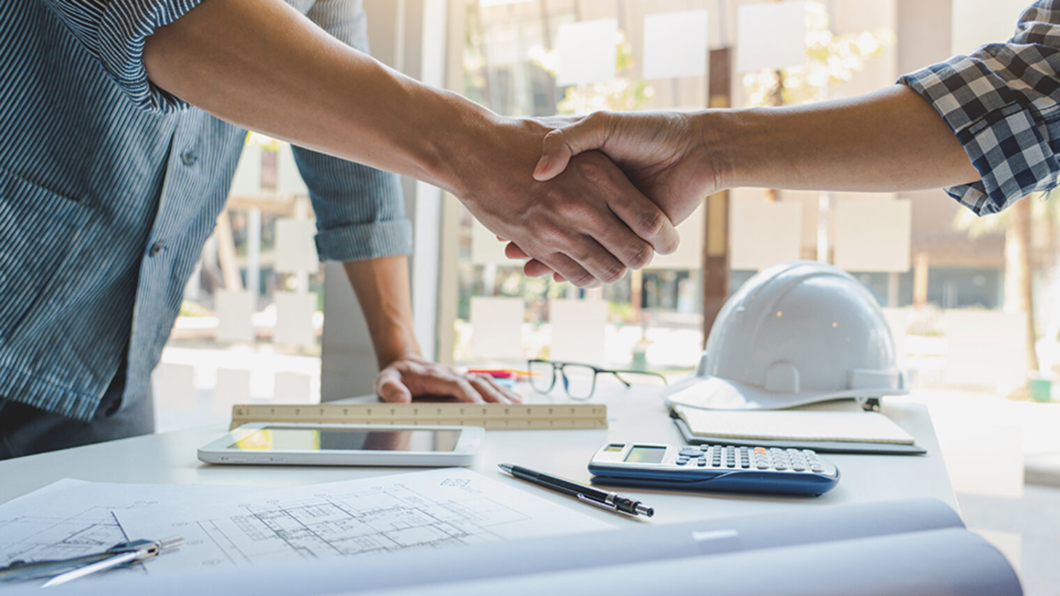 Architect and engineer construction workers shaking hands while